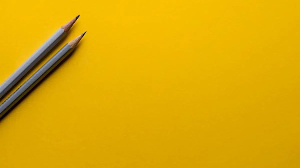 Two grey pencils on a yellow background to illustrate branding a startup