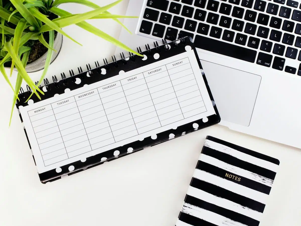 A black and white weekly planner with a notebook and laptop