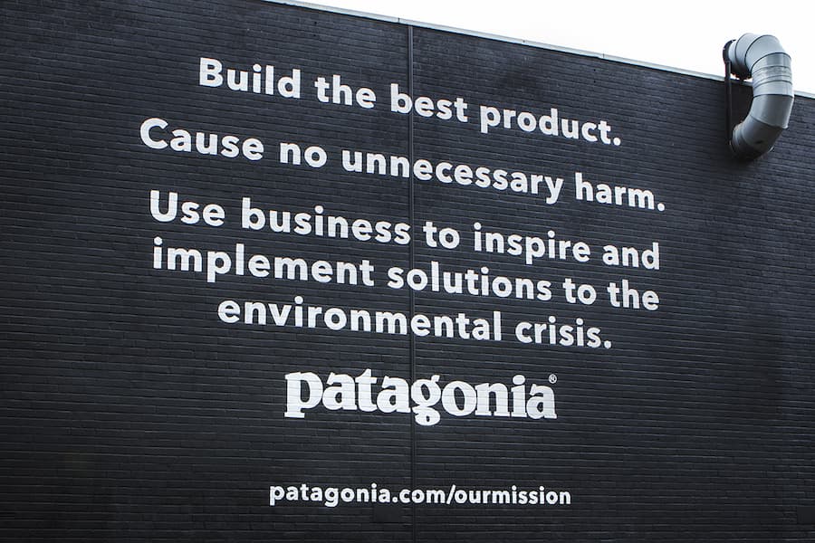 Patagonia brand and mission statement printed on a brick wall.