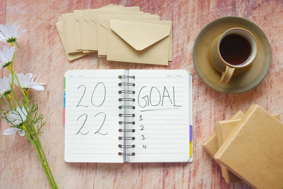 Open diary on a wooden table reading '2022 goal' for marketing trends in 2022